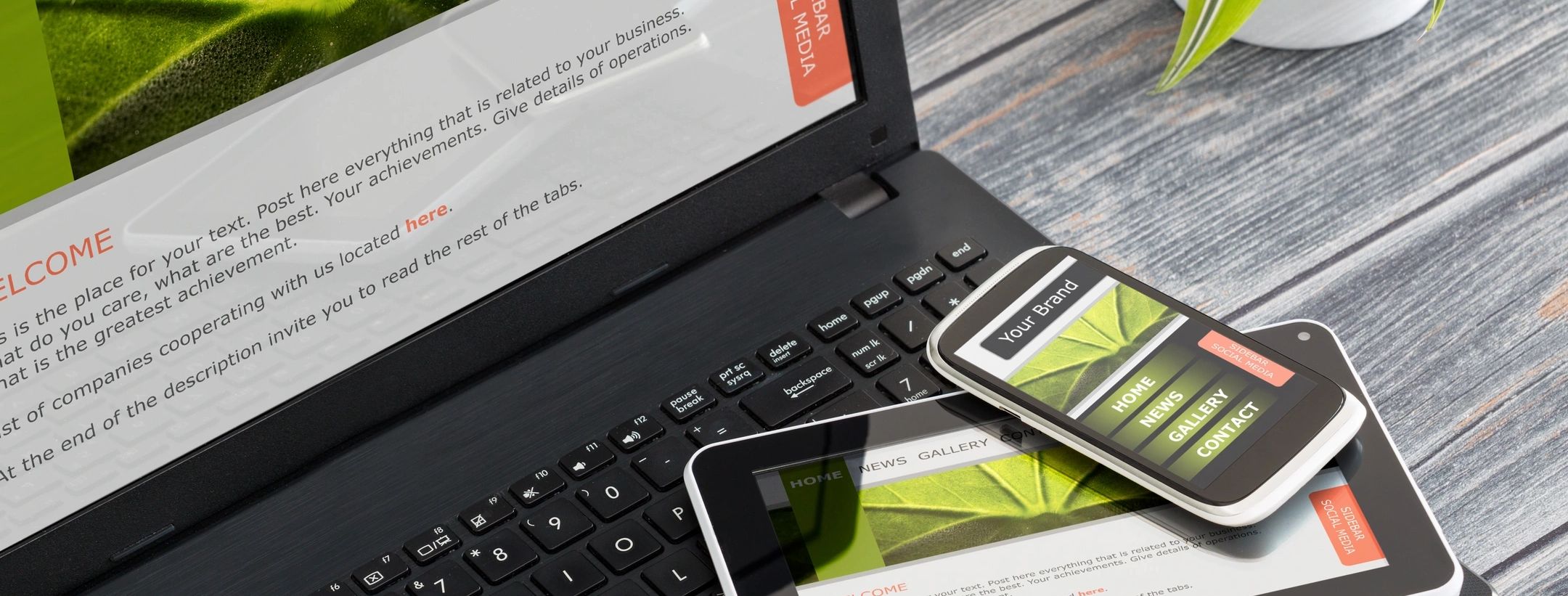 Laptop, tablet, and smartphone displaying a responsive website on a wooden table.