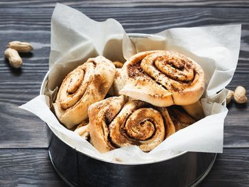 Freshly baked cinnamon rolls in a parchment-lined tin.