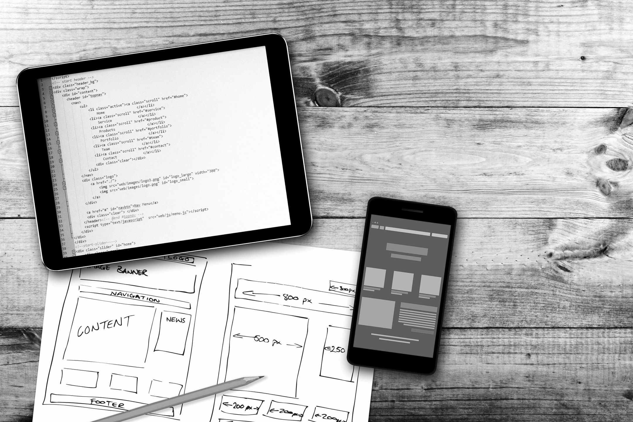 Tablet, phone and paper on a wooden desk