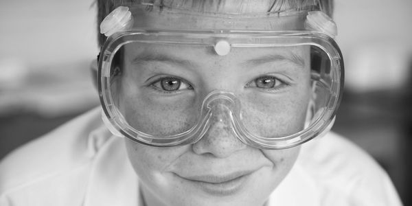 Close-up of a smiling child wearing safety goggles.