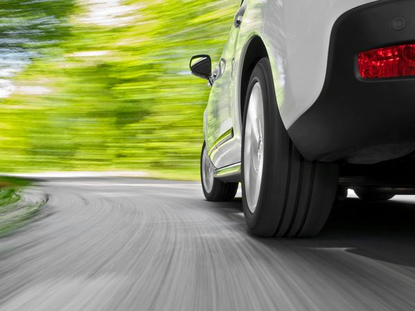 The side view of a car driving along a country road 