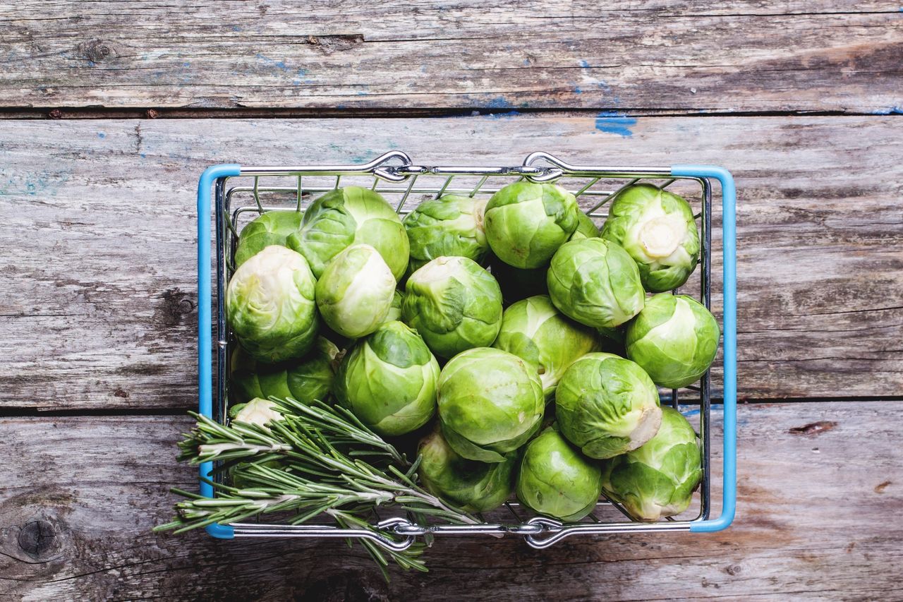 Brussels sprouts and fresh rosemary in a blue metal basket