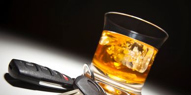Keyw on table with a glass of bourbon on ice to symbolize drinking and driving may result in a DUI.
