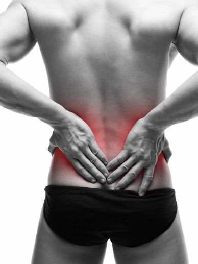 Man holding his lower back in pain, highlighting the affected area in red.