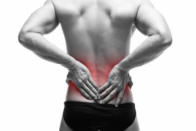 Male holding their lower back with the painful area highlighted by a superimposed red glow