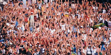 Crowd of excited people cheering with hands raised.