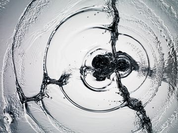Close-up of water ripples and splashes creating circular patterns.