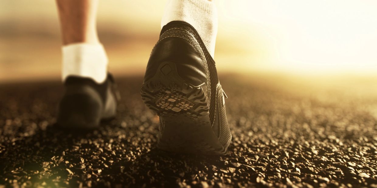 Close-up of running shoes on gravel in warm light.