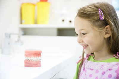 child looking at teeth model in dental office