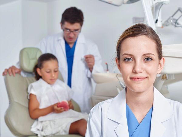 Dentists and a patient who has dental insurance, is receiving treatment. US Dental Adviser.