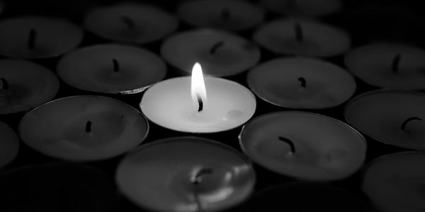 A single lit candle among many unlit ones.