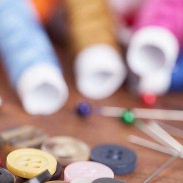 Colorful buttons and sewing pins scattered on a wooden surface.
