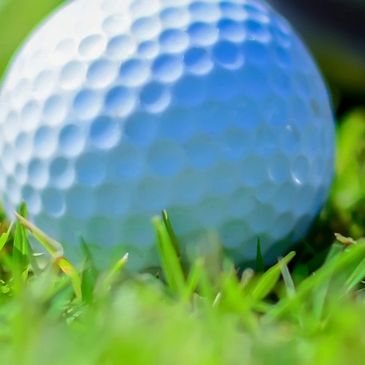 Golf ball and clubs on grass.