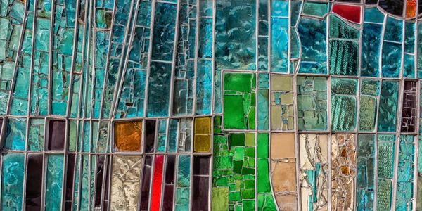 Aerial view of colorful agricultural fields divided into geometric sections.