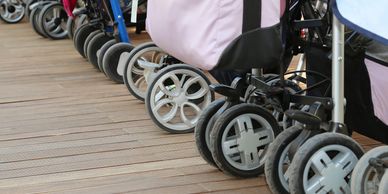 Row of baby stroller wheels lined up on wooden floor.