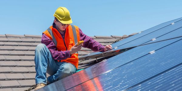 Man Hanging Solar Panels on Roof