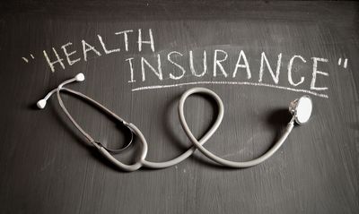 Stethoscope on a board that has "health insurance" written on it. 