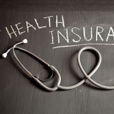 A stethoscope on a chalkboard with the words 'Health Insurance'.