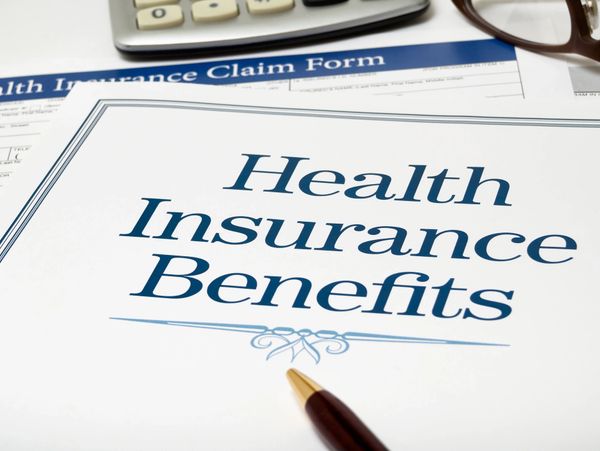 Health insurance benefits document with pen and glasses.