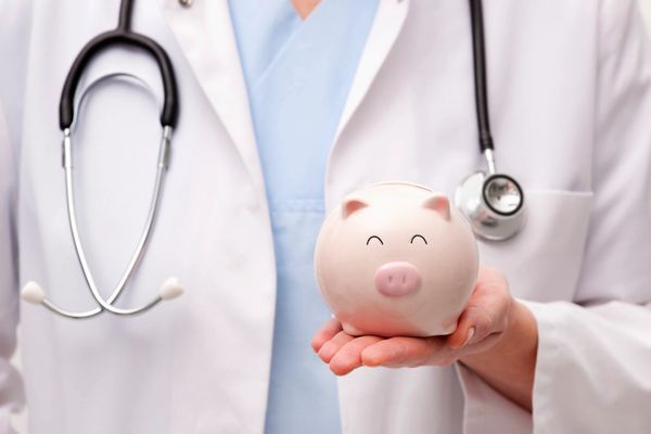 Doctor holding a piggy bank symbolizing healthcare savings.