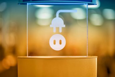 A glowing plug and socket symbol inside a transparent display stand.