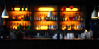 Picture of an empty bar with lighted bottles on shelf in background