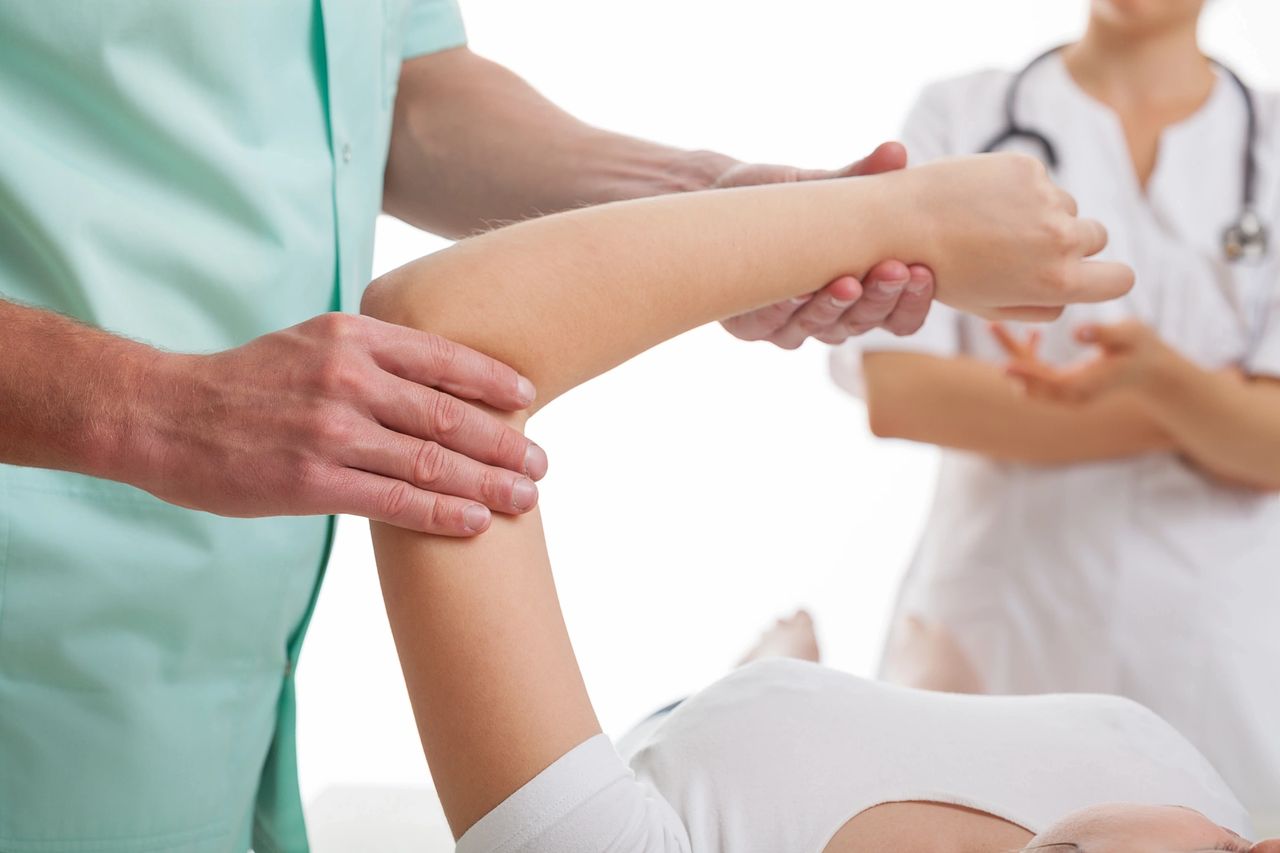 A physical therapist assisting a patient with arm exercises.