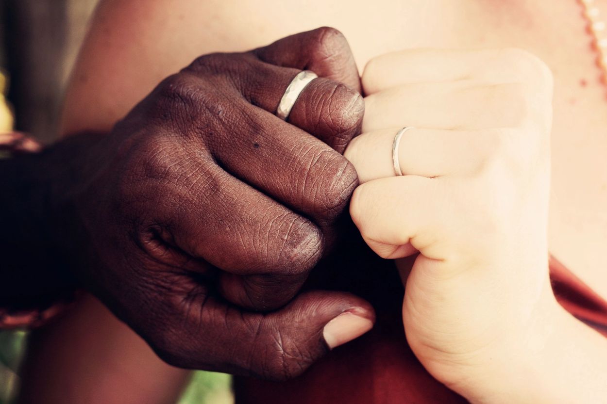 Two hands with wedding rings intertwined.