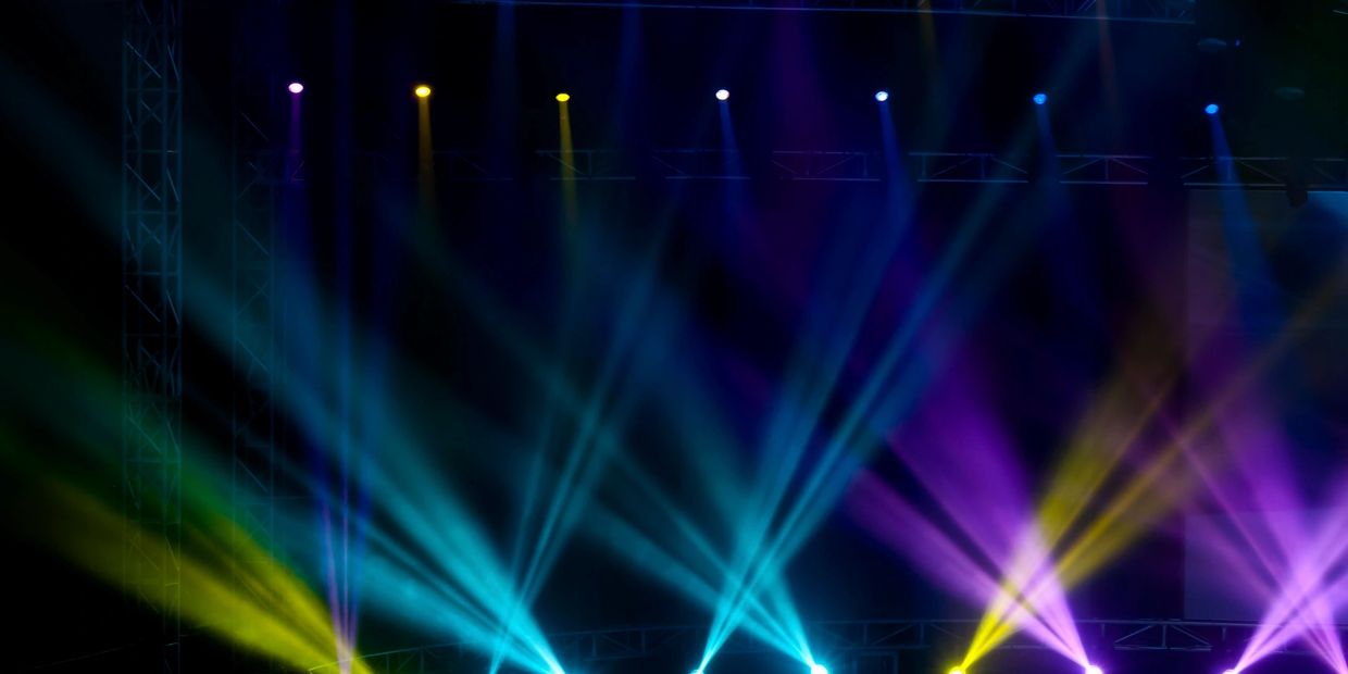 Colorful stage lights shine in blue, yellow, and purple beams.