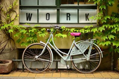 Bicycle parked below window with 'WORK' sign.