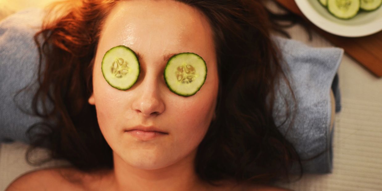 Woman relaxing with cucumber slices on her eyes during a facial treatment.