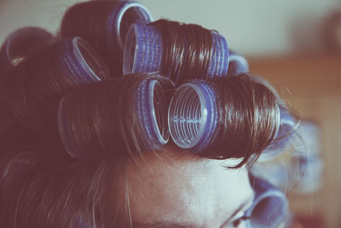 Close-up of hair with blue rollers for styling.
