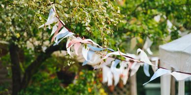 Colorful fabric bunting hanging on a tree branch outdoors.