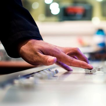 Hand adjusting audio mixer sliders.
