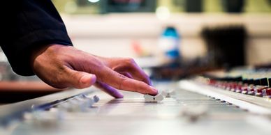 Hand adjusting a knob on a sound mixing console.