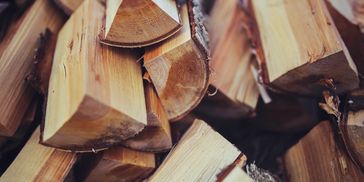Close-up of stacked firewood pieces with rough bark and clean cuts.