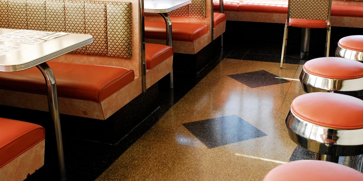 Retro diner seating with orange booths and stools.