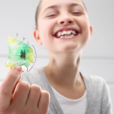 Happy child with a retainer to help shape teeth during the early treatment phase.