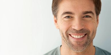 Close-up of a smiling man with light stubble and blue eyes.