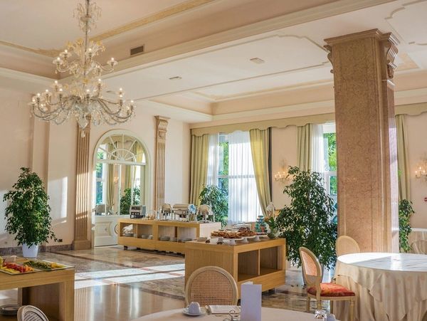 Elegant dining room with chandeliers, large windows, and buffet tables.