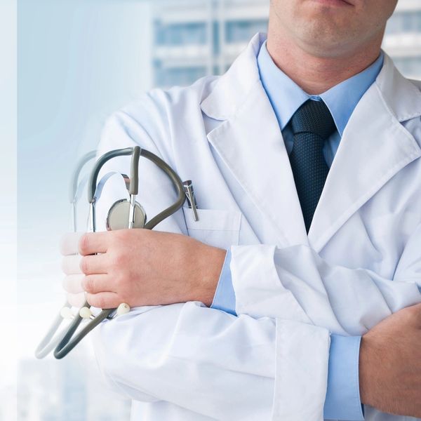 Doctor in white coat holding a stethoscope with arms crossed.