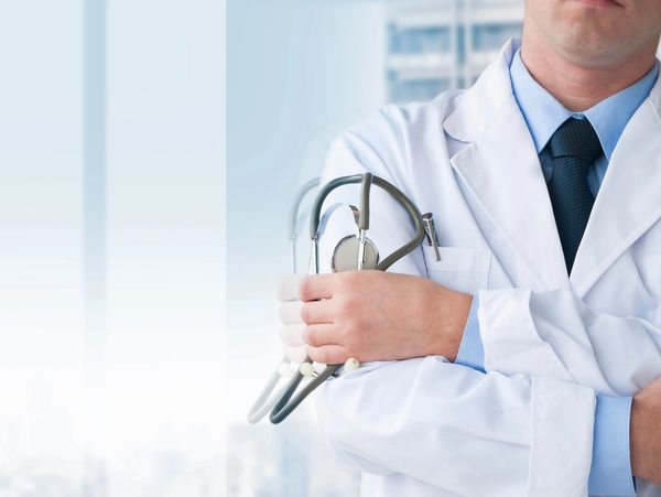 Doctor in white coat holding a stethoscope with arms crossed.