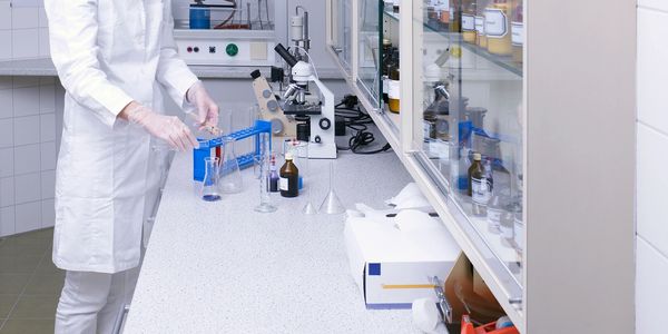 Lab technician working with glassware and chemicals in a laboratory.