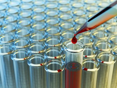 Red liquid drop falling into a test tube among many empty ones.