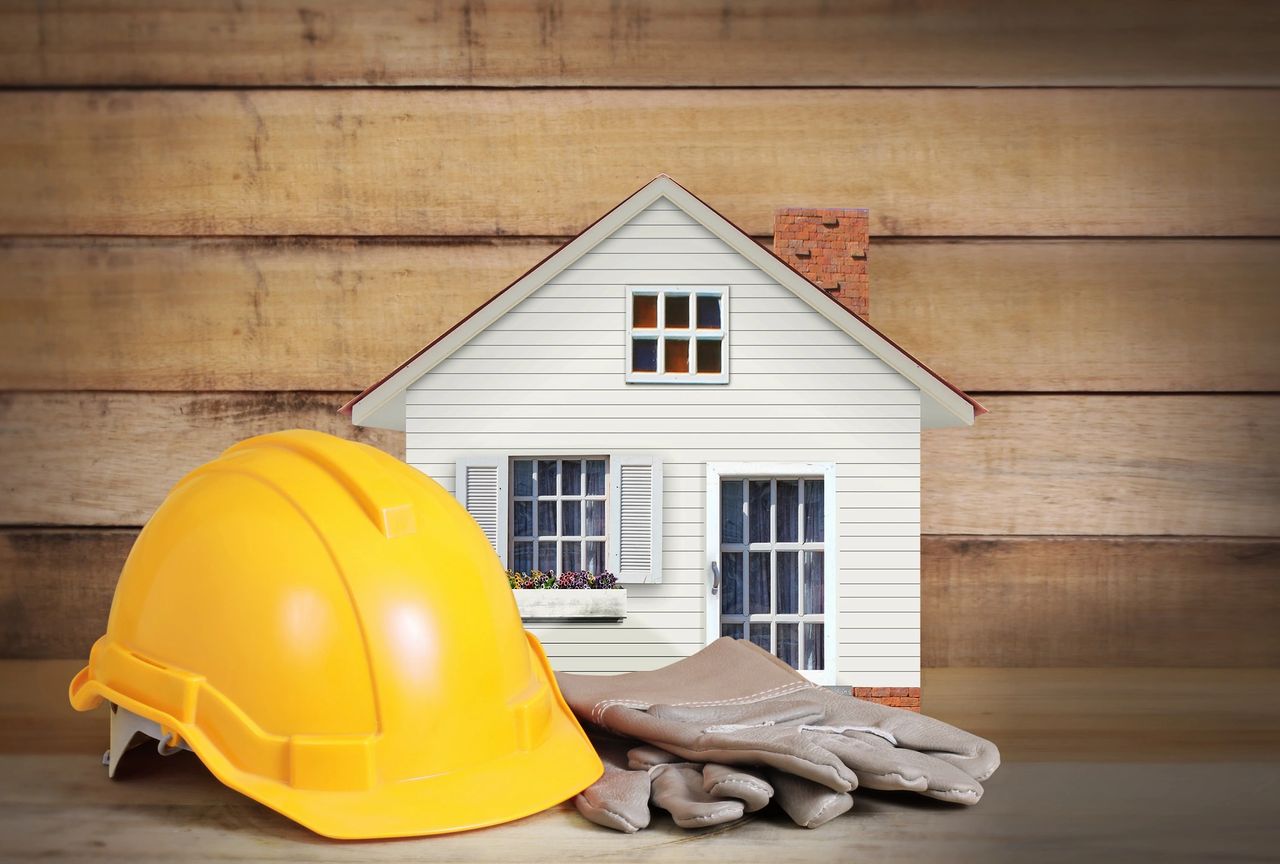A home, a yellow hard hat and construction gloves.