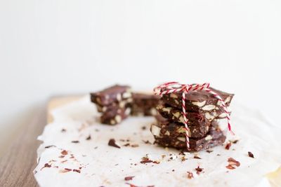 Stack of chocolate oat bars tied with red and white string on parchment paper.