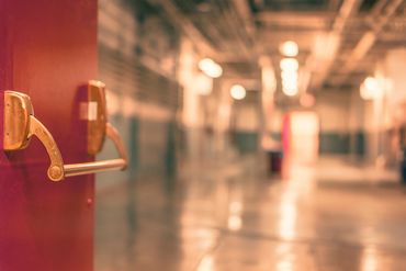 Open door handle with a blurred hallway background.