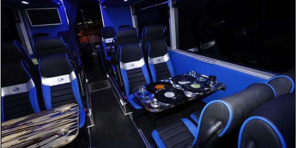 Modern bus interior with blue and black seats and vinyl record-themed tables.