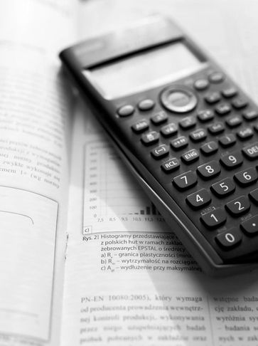 Scientific calculator resting on an open textbook with graphs and text.