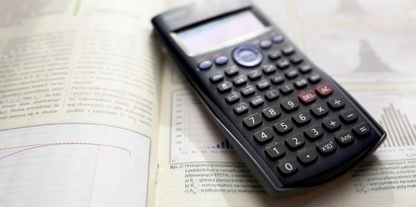 A scientific calculator resting on open textbooks with graphs and text.